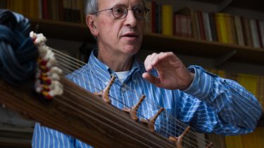 Staff playing world music instrument in music library