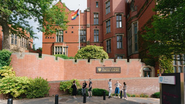 The LGBT+ flag outside of the red, bricked Firth Court