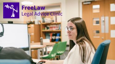 FreeLaw student at a computer in the Support through court office in Bartolome House. Asking a question of a fellow volunteer